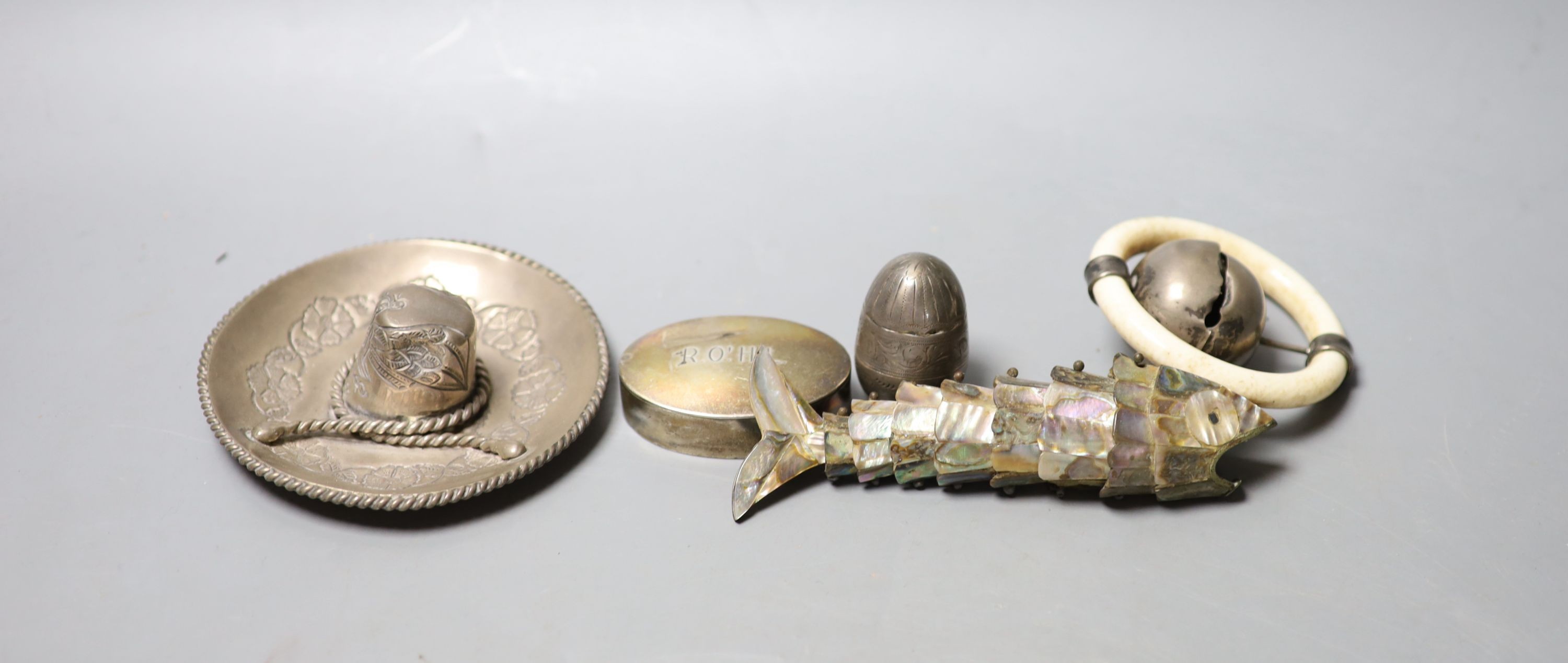 A silver and ivory baby's rattle with teething ring and a Mexican sterling 'hat' snuffer and three other items, including a mother of pearl mounted articulated fish and a silver pill box.